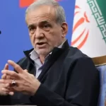 ایرانی صدر مسعود پزشکیان ڈائس پر لگے مائیکروفونز کے سامنے بیٹھے ہوئے گفتگو کر رہے ہیں اور اپنے دونوں ہاتھوں کی انگلیاں آپس میں ملائے اشارہ کر رہے ہیں